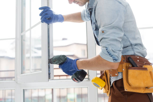 Gloved installer drilling a new white window frame into place for window installation in Burlington - WI